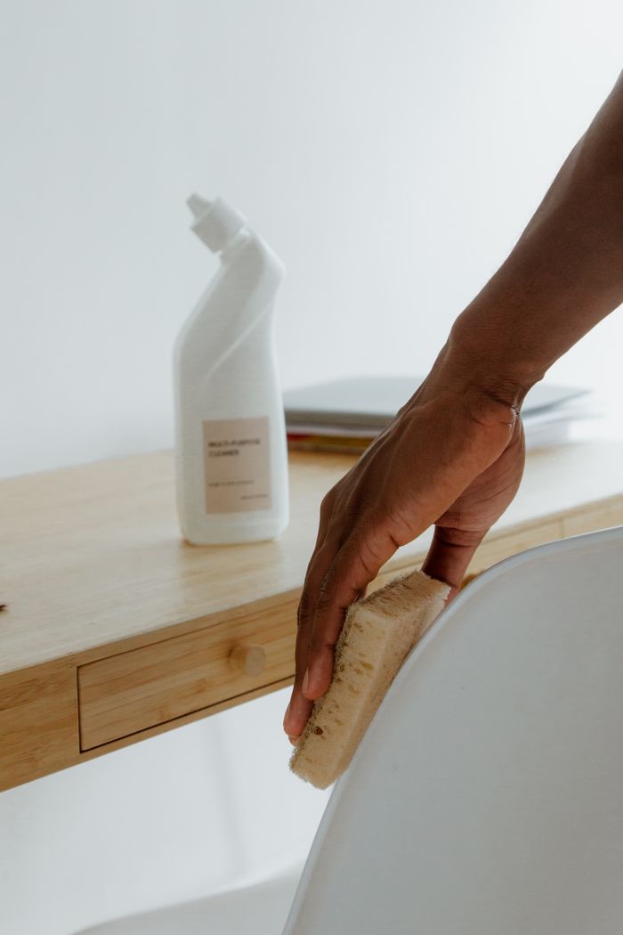 The Art of Drawing Readers In: Your attractive post title goes here Minimalist room with a person cleaning a chair using a sponge and cleaning product.