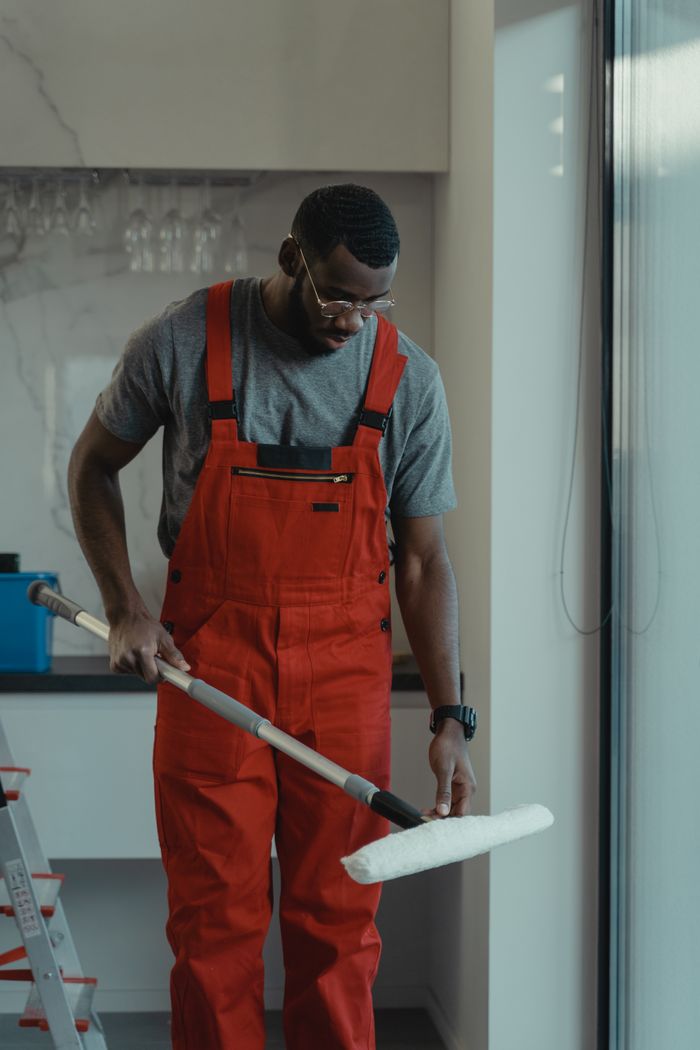 Crafting Captivating Headlines: Your awesome post title goes here Man wearing red overalls using a mop indoors, depicting cleanliness and manual work.