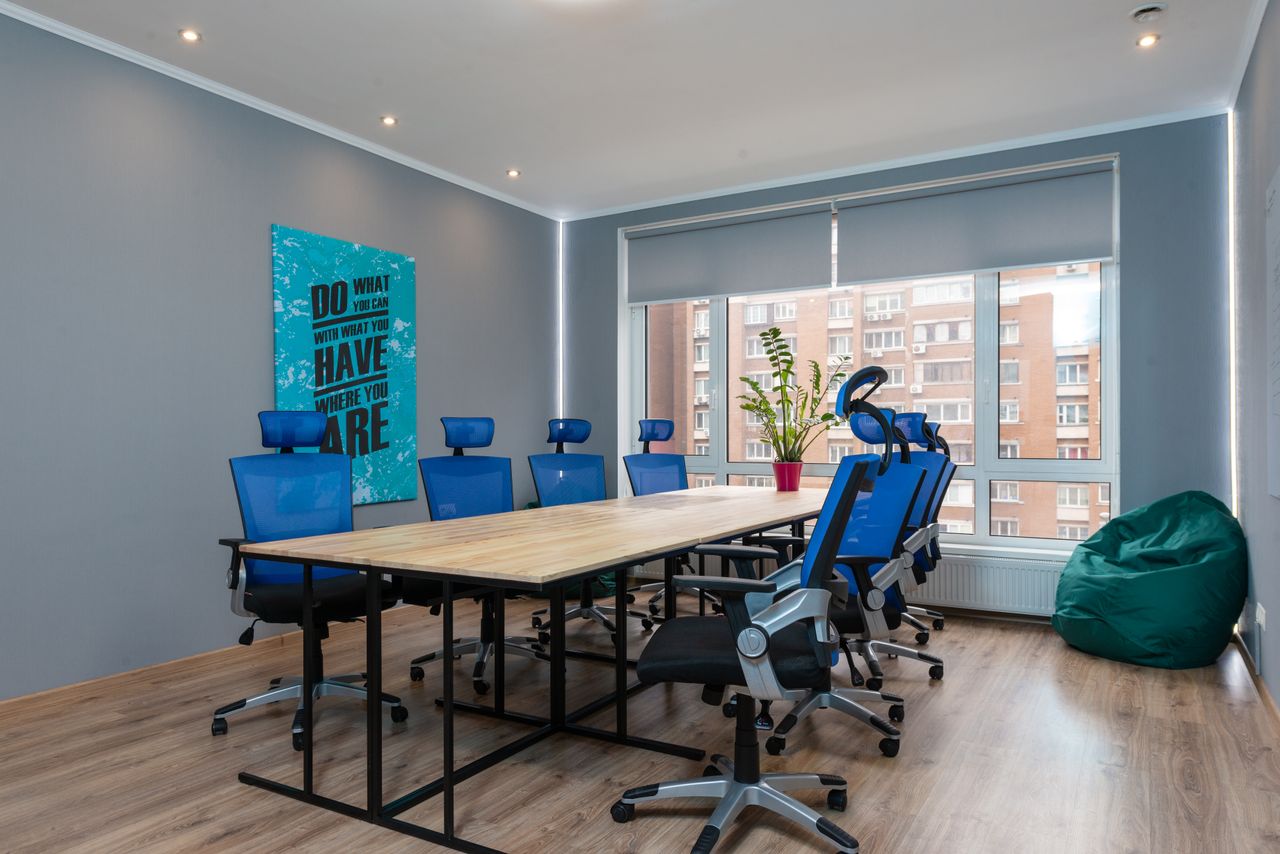 services-01 Blue armchairs at wooden table placed in modern conference room with decorative signboard with inscription and window in stylish office building