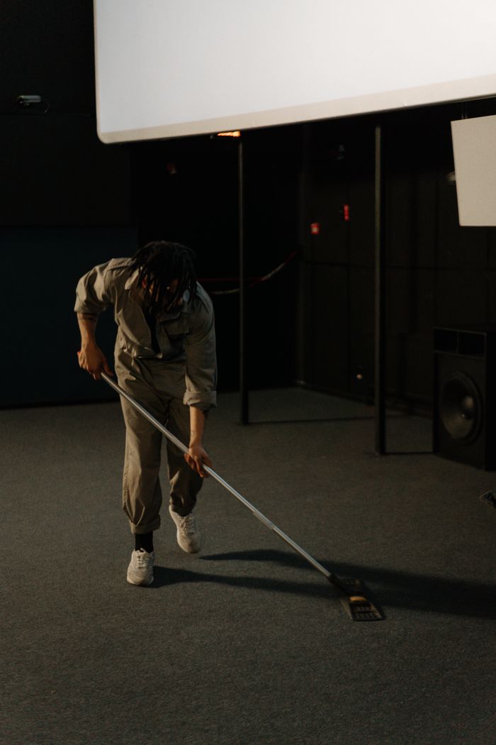 services-01 A person cleaning the carpet in an empty cinema, highlighting maintenance work.